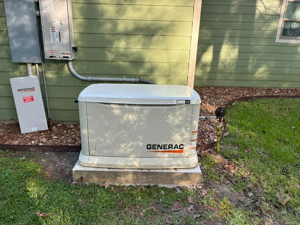 Generac standby generator on a concrete pad beside green house siding